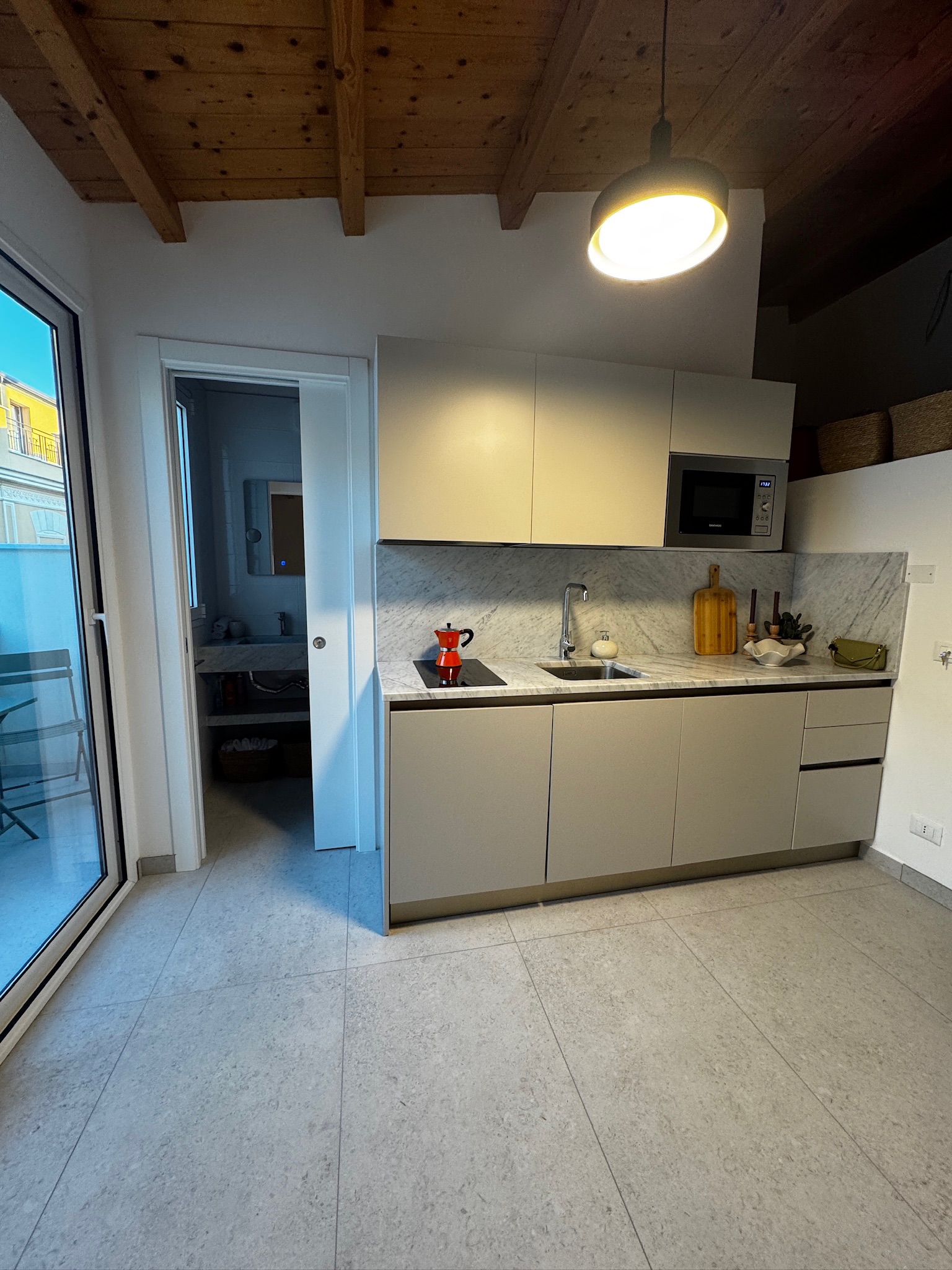 Kitchen with exposed wood beam ceiling, terrace door beyond